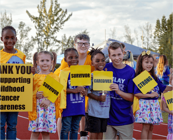 group of children on track holding gold inspirational signs