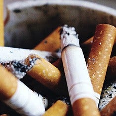 Close up shot of several used cigarettes and ashes in an ashtray. 