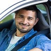 Smiling man driving in car with hand out the window