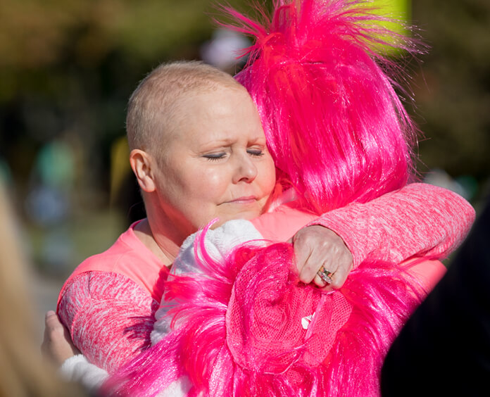 Двое людей, одетых в розовое, обнимаются на мероприятии "Делаем успехи против рака молочной железы"