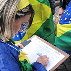 Picture of a young woman signing forms draped in the national colors of the Brazilian flag.