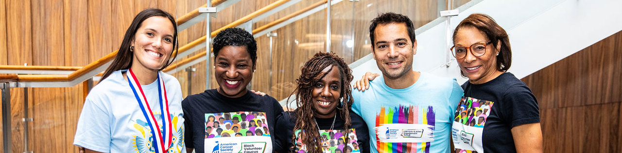 Five smiling volunteers posing together indoors