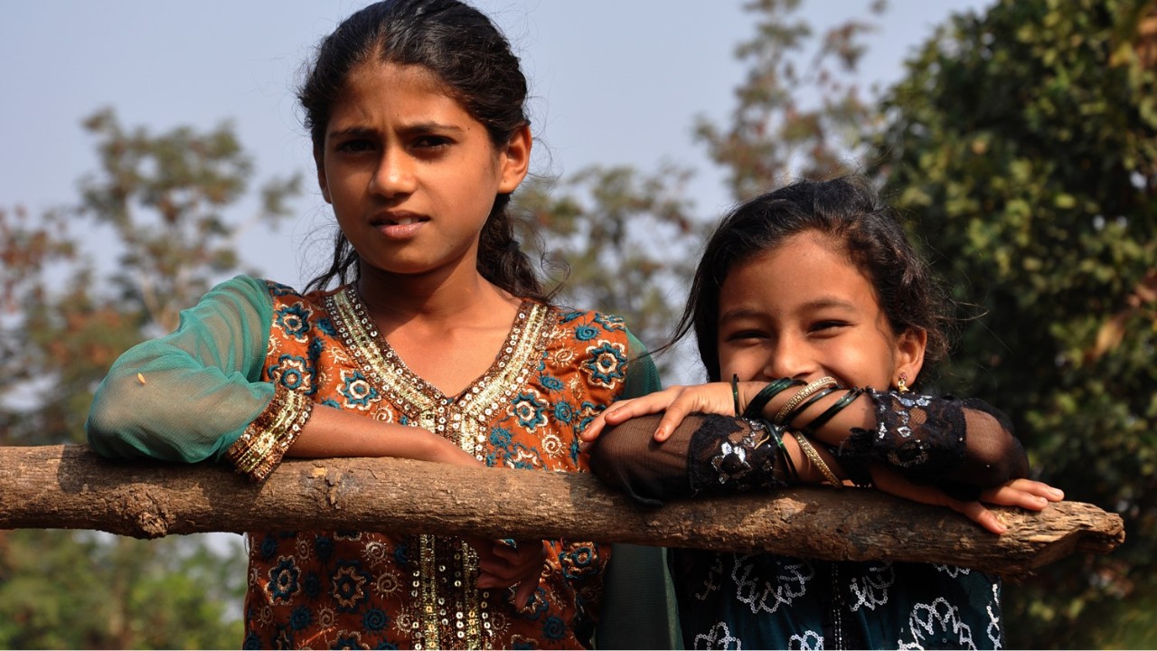 Two young Indian girls leaning on a branch