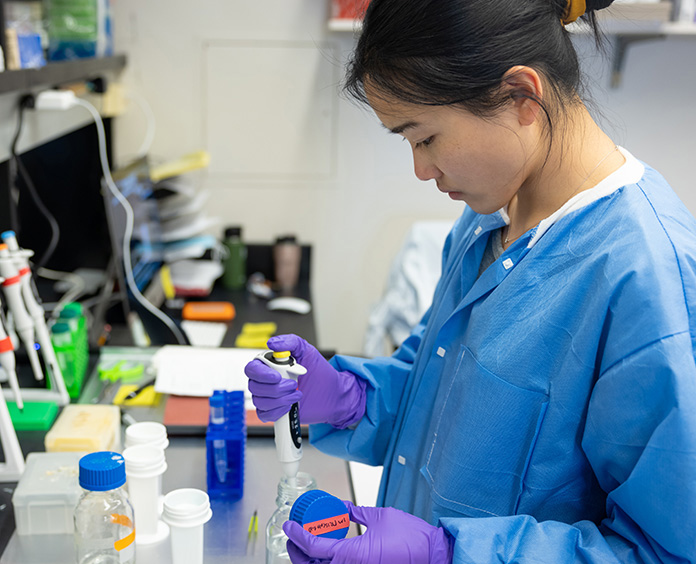 Asian woman wearing lab coat and gloves 
