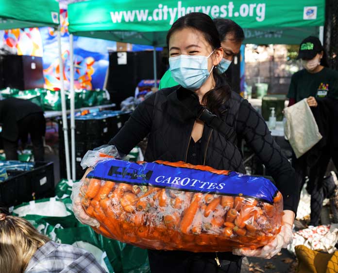 woman holding large bag of carrots at the City Harvest Market