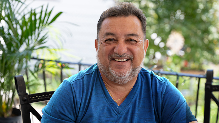 Smiling man in blue shirt sitting outdoors.