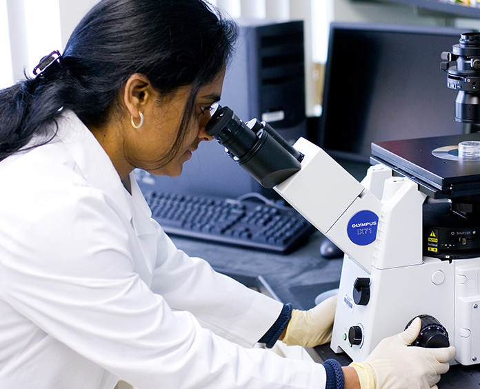 Indian Female Scientist looking through microscope