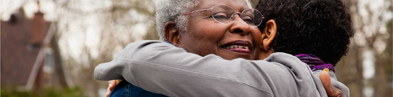 Black women hugging another person outside