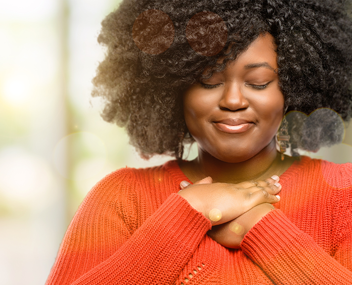 black woman wearing orange sweater with hands across chest
