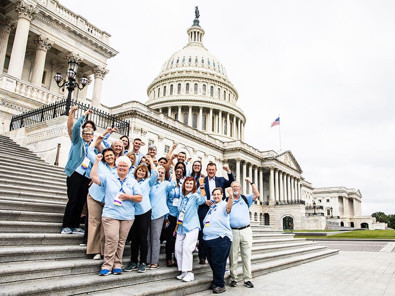Group posing on steps in front of US Capitol building.