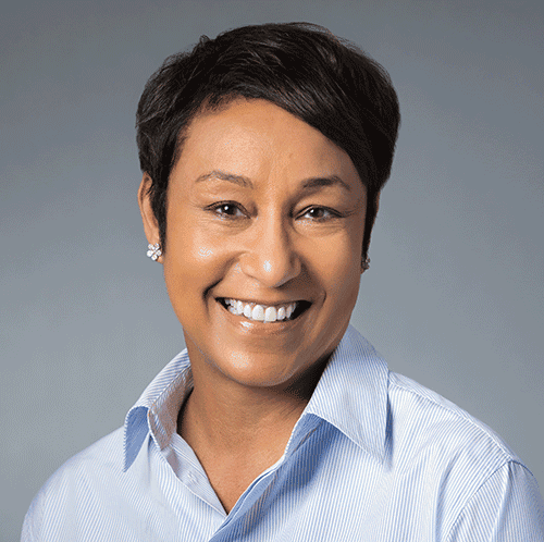 Smiling woman with short hair wearing light blue collared shirt.