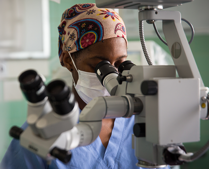 black woman researcher looking at microscope