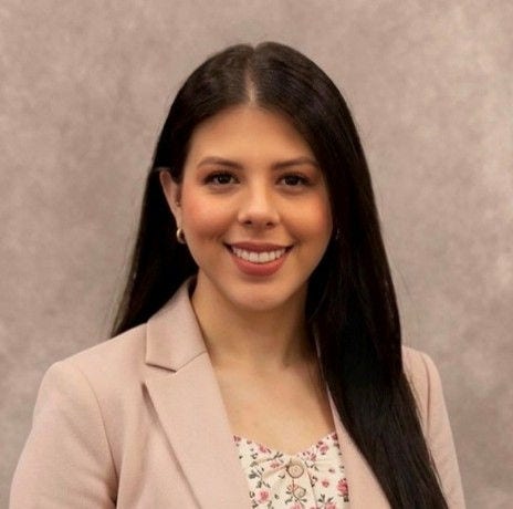 Smiling woman in a pink blazer and floral top.