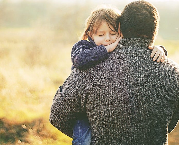 A father carrying his child in a sunny field