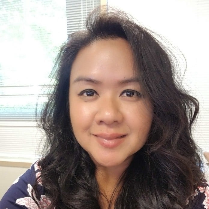 young woman with tan skin and long wavy brown hair, wearing blue flowered top