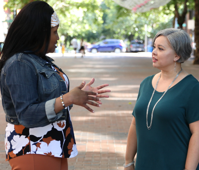 two women talking in the middle of city street