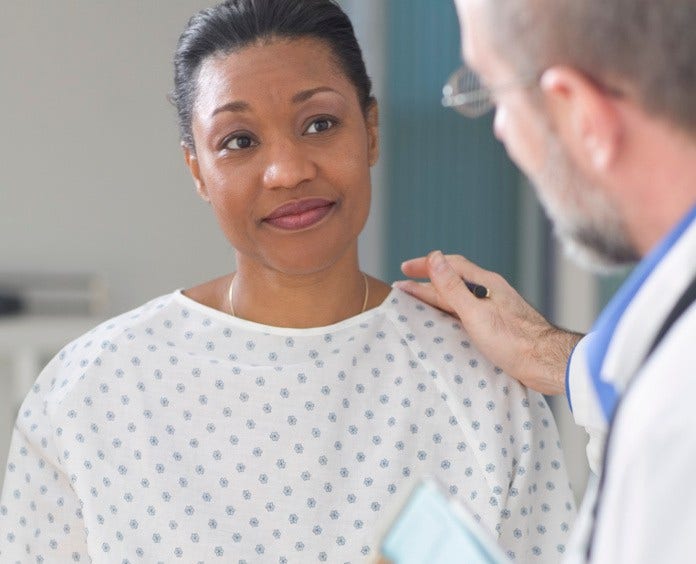 woman in hospital gown being comforted by doctor