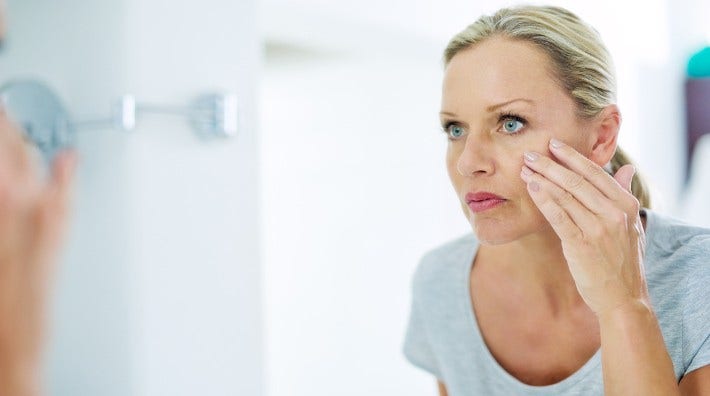 woman checks skin of her face in a mirror