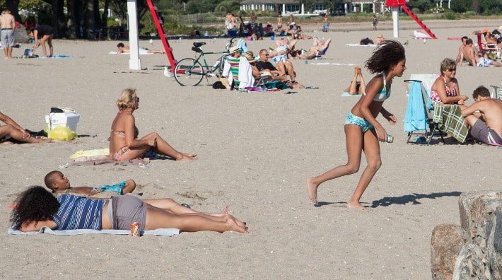 young Latina girl runs on a crowded beach