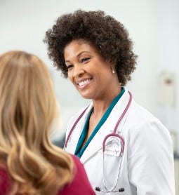 doctor smiles while talking to patient in exam room