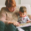 caucasian grandmother reading a book with her grandchild 