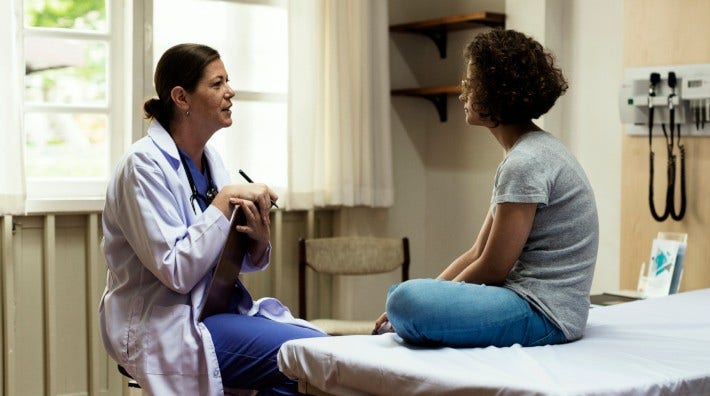 female doctor talking to a young woman in exam room