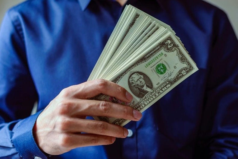 blue shirt holding stack of $2 bills
