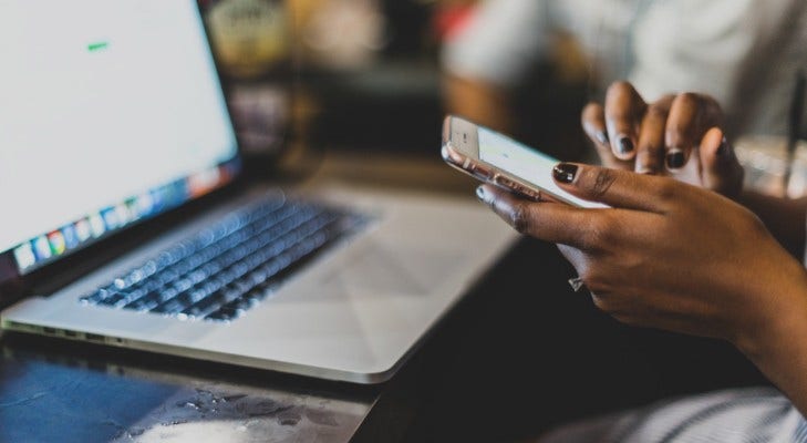 black woman on cell phone in front of laptop