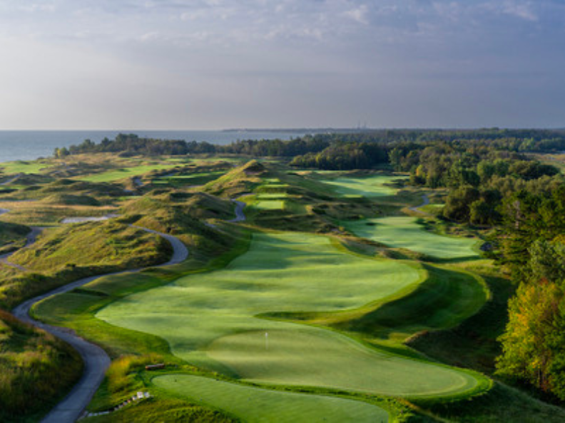 Scenic golf course with rolling hills and lake view.