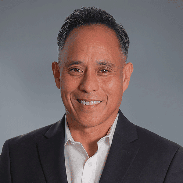 Smiling man wearing a dark suit and white shirt.