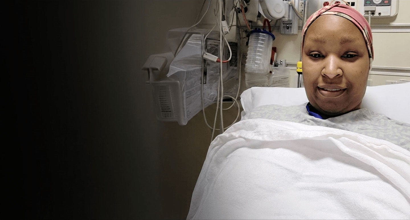 Paciente en una cama de hospital con pañuelo en la cabeza, sonriendo a la cámara.