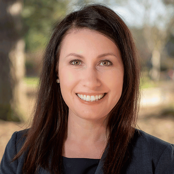 Woman smiling outdoors in professional attire.