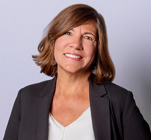 Professional woman with brown hair wearing black blazer smiling