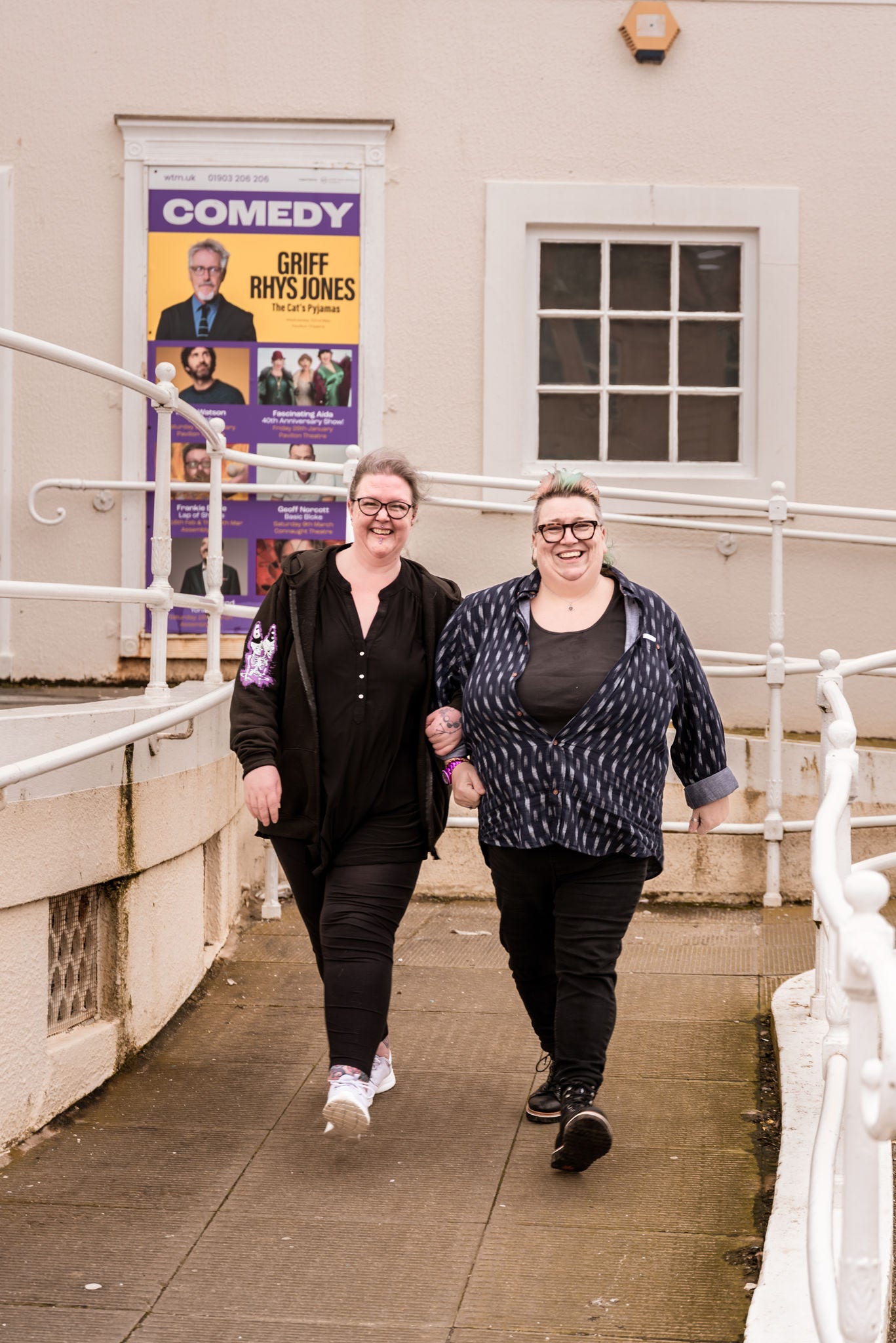 2 large women walking both dressed in black with glasses