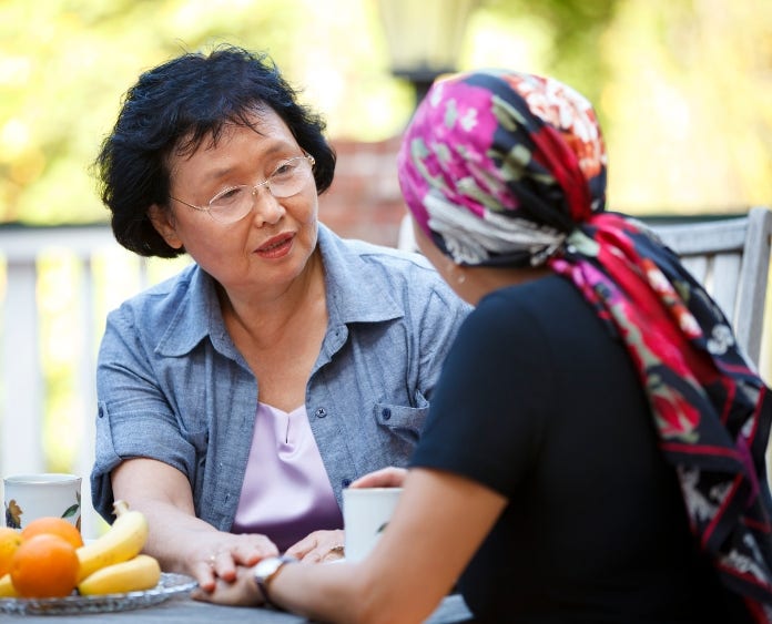 woman comforts a female cancer patient at outdoor table