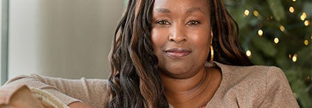 Mujer sentada en interiores con expresión serena y cabello largo.