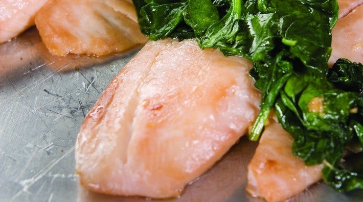 pieces of skillet tilapia with sautéed spinach on top