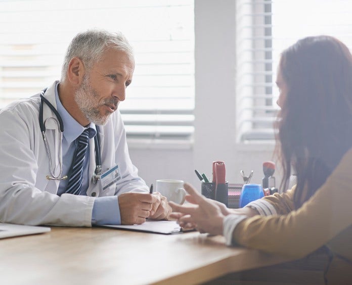 doctor sitting behind desk and talking with his patient