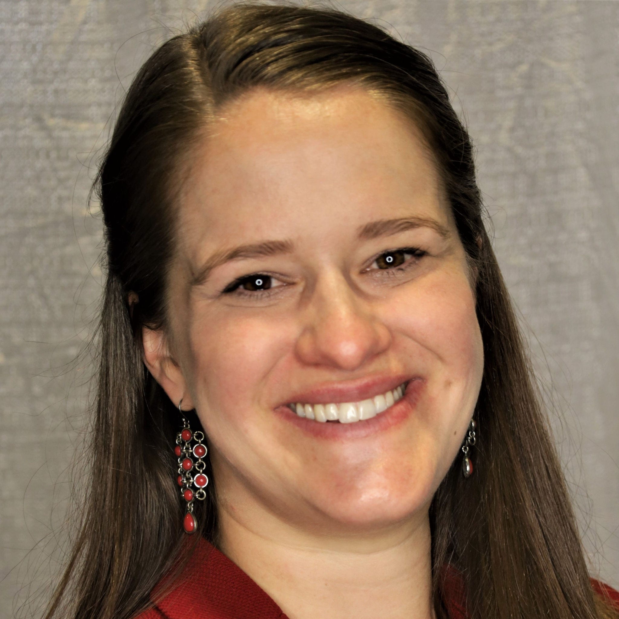 headshot of Danielle "Dani" Morrow, long brown hair, red earrings