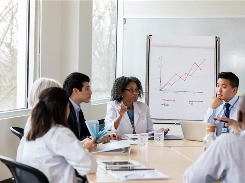six doctors talking around a conference table