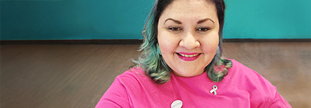 Mujer sonriente con cabello de colores y una camiseta rosa brillante.