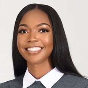 young Black woman with long hair gray sweater with white pointed collar