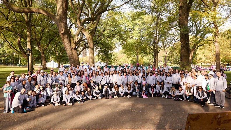 Large group gathered together in a park under trees.