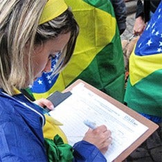 Picture of a young woman signing forms draped in the national colors of the Brazilian flag.