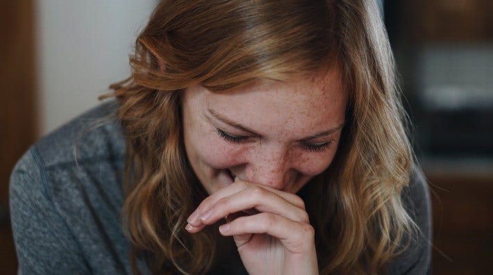 young woman covering her mouth while laughing