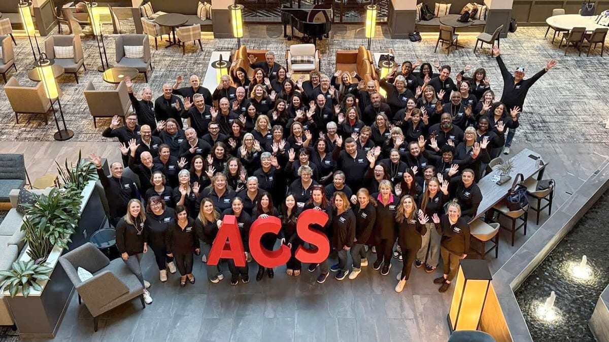 Large group waving around red ACS letters in lobby.