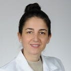 woman in white lab coat with dark hair in bun