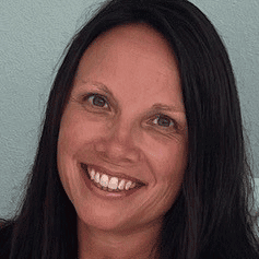 A smiling woman with long dark hair against a light background.