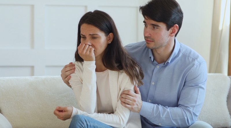 Imagen estática del video mostrando un acercamiento de una pareja sentada en un sofá con un semblante de preocupación