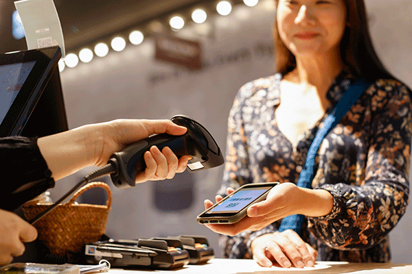 Customer paying with phone at checkout counter.